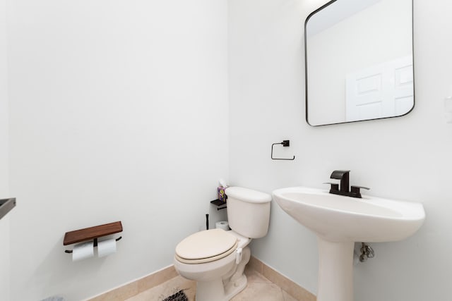 half bathroom with tile patterned floors, toilet, baseboards, and a sink