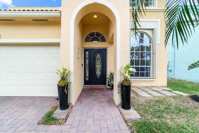 entrance to property with driveway, stucco siding, and an attached garage