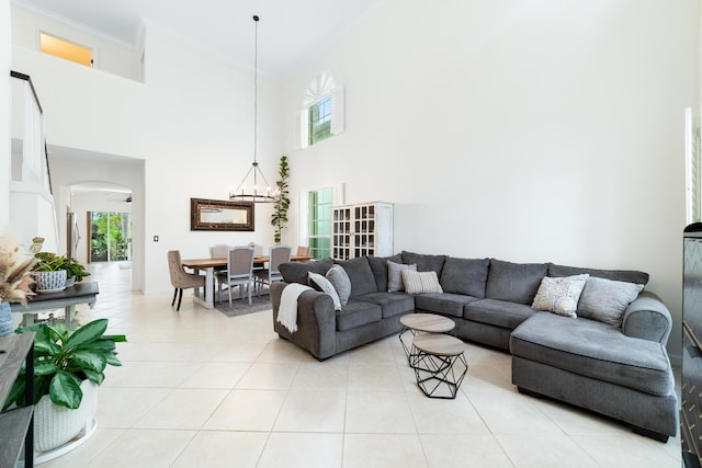 living area with light tile patterned flooring, crown molding, arched walkways, and a healthy amount of sunlight