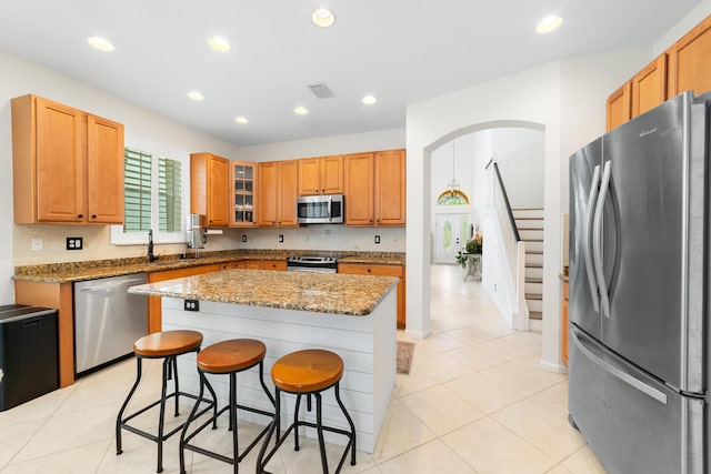 kitchen featuring visible vents, a kitchen bar, appliances with stainless steel finishes, arched walkways, and a center island