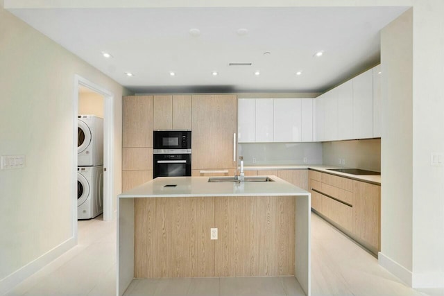 kitchen with modern cabinets, black appliances, a sink, and light brown cabinets