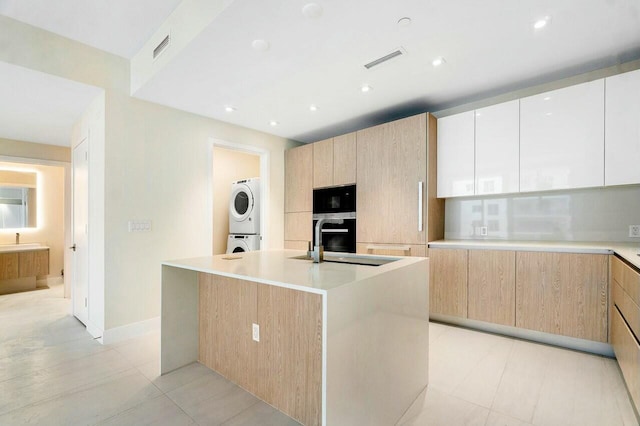 kitchen with modern cabinets, stacked washing maching and dryer, and light brown cabinetry