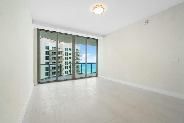 spare room featuring baseboards and expansive windows