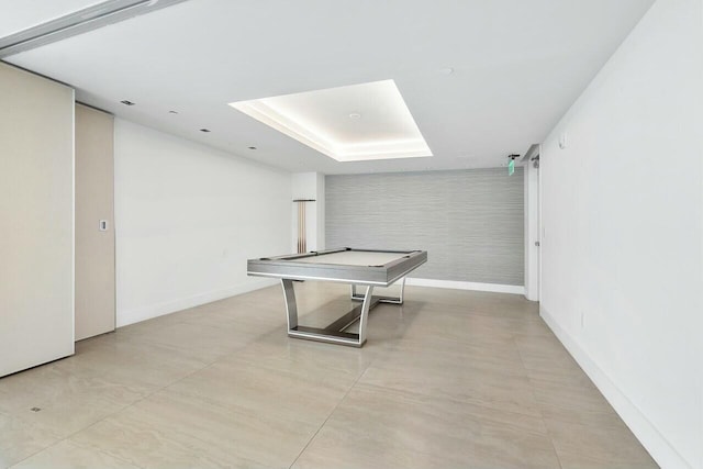 game room with baseboards and a raised ceiling