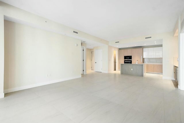 unfurnished living room featuring baseboards and visible vents