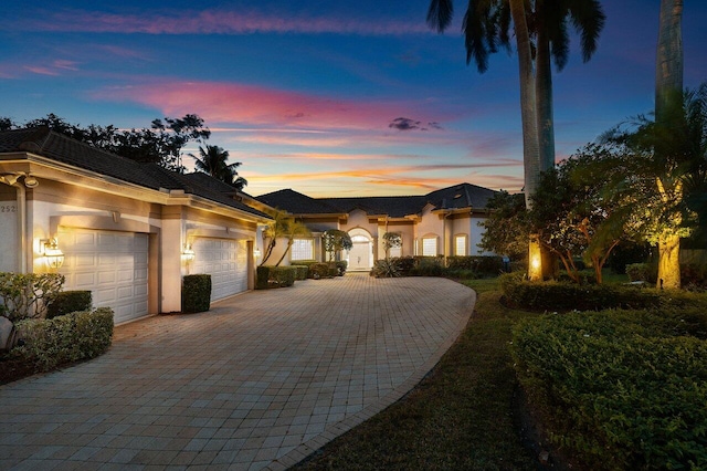 view of front of property with stucco siding, a garage, and decorative driveway