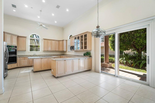 kitchen with visible vents, crown molding, a towering ceiling, stainless steel appliances, and light brown cabinets