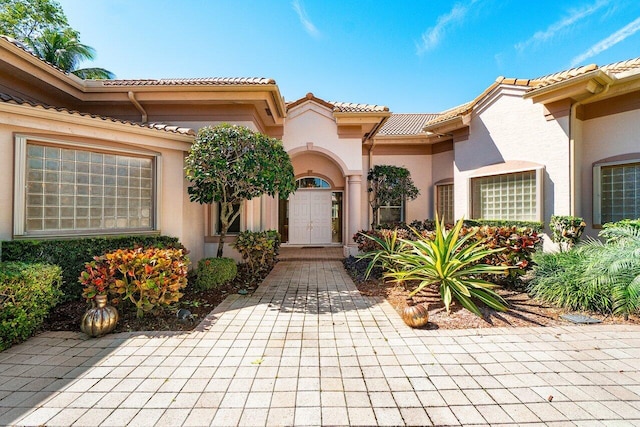 view of exterior entry with a tile roof and stucco siding