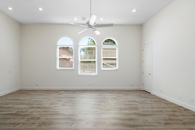 unfurnished room featuring wood finished floors, plenty of natural light, and ceiling fan