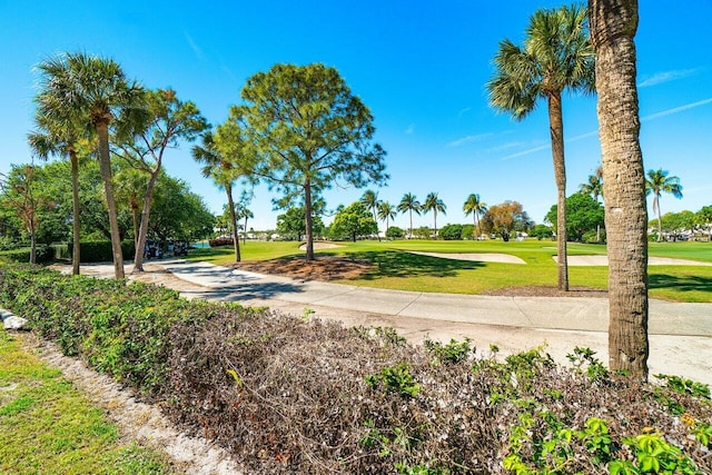 view of property's community with view of golf course and a lawn