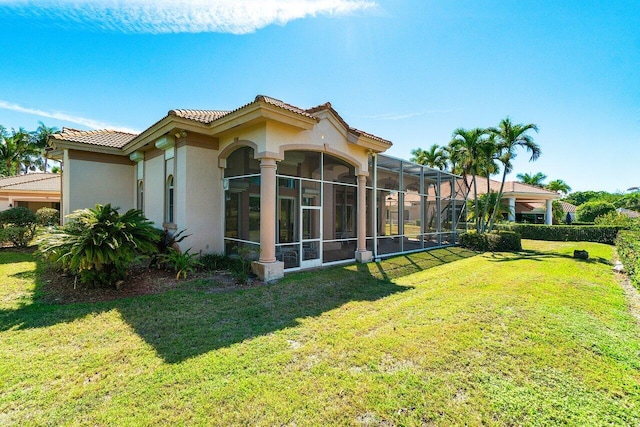 back of property with a tile roof, stucco siding, a lanai, and a yard