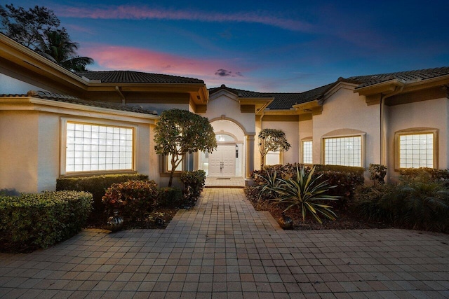 exterior space with a tile roof and stucco siding