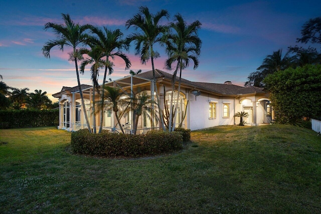 view of home's exterior with stucco siding, a yard, and a lanai
