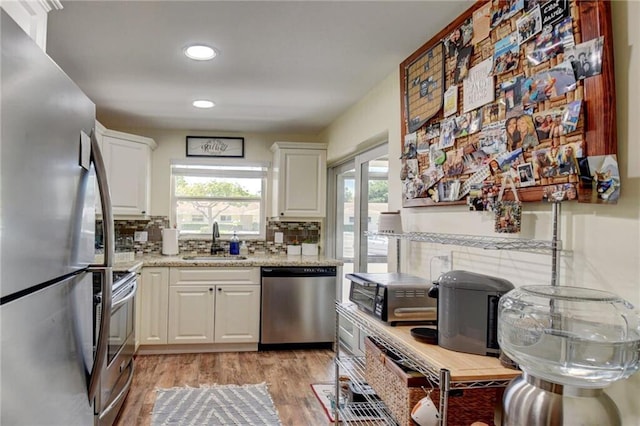 kitchen featuring light wood-type flooring, white cabinets, a sink, and stainless steel appliances