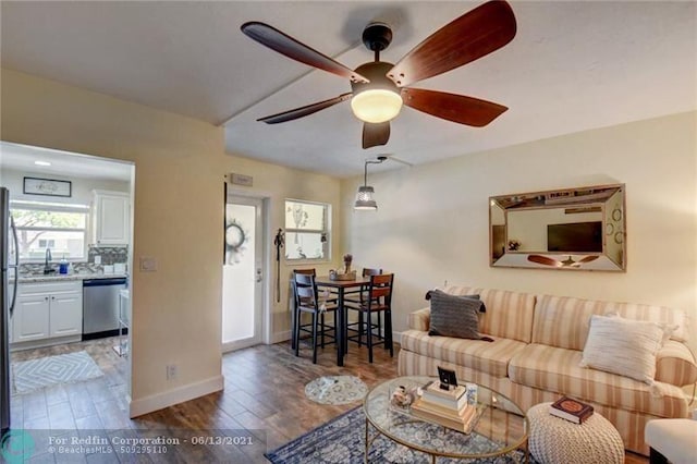 living room with a ceiling fan, baseboards, and wood finished floors