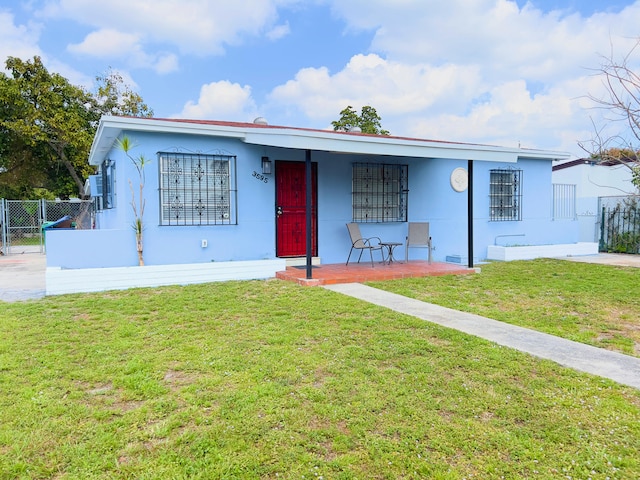 single story home with stucco siding, covered porch, fence, and a front yard