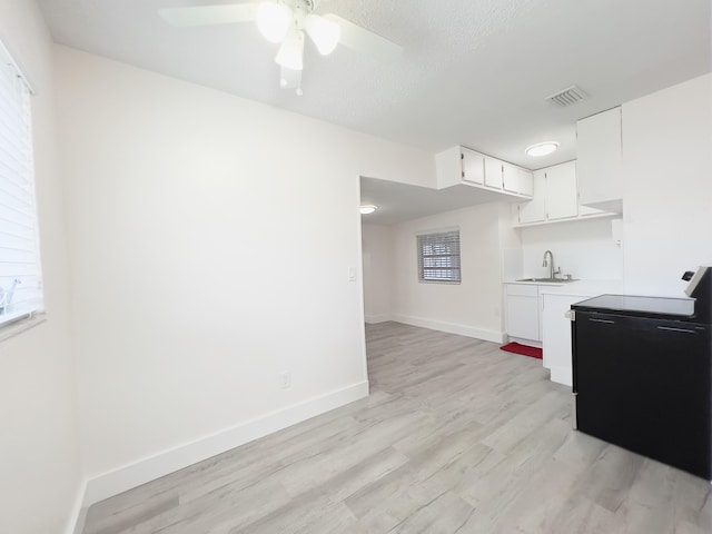 kitchen featuring white cabinets, visible vents, light countertops, light wood finished floors, and black / electric stove