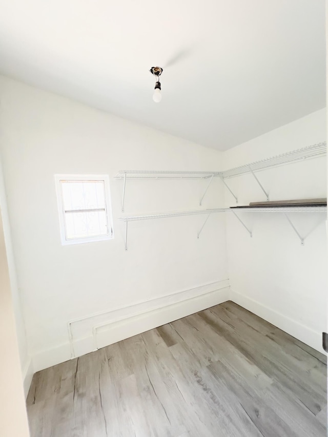 walk in closet with vaulted ceiling and light wood finished floors