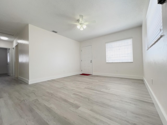 spare room featuring light wood-type flooring, baseboards, ceiling fan, and visible vents