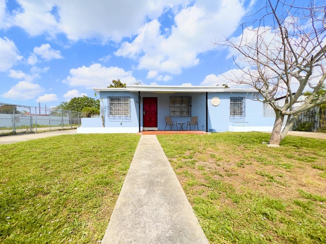 single story home with concrete driveway, stucco siding, fence, a front yard, and a porch
