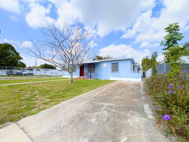 view of front of property featuring driveway, a front yard, fence, and stucco siding
