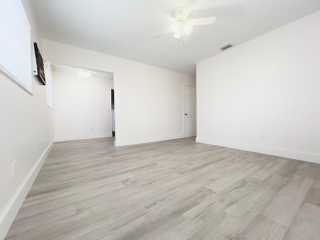 empty room featuring light wood-type flooring, visible vents, baseboards, and ceiling fan
