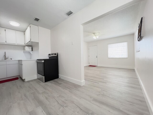kitchen featuring visible vents, white cabinets, light wood-style floors, and stainless steel range with electric stovetop