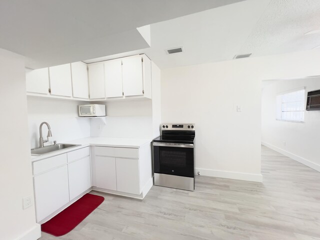 kitchen featuring white cabinets, light countertops, light wood finished floors, stainless steel range with electric cooktop, and a sink