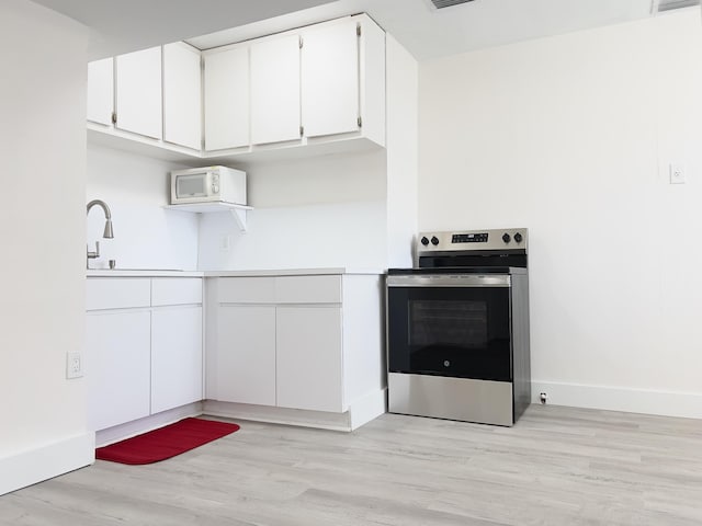 kitchen with a sink, white cabinetry, light wood-type flooring, electric stove, and white microwave