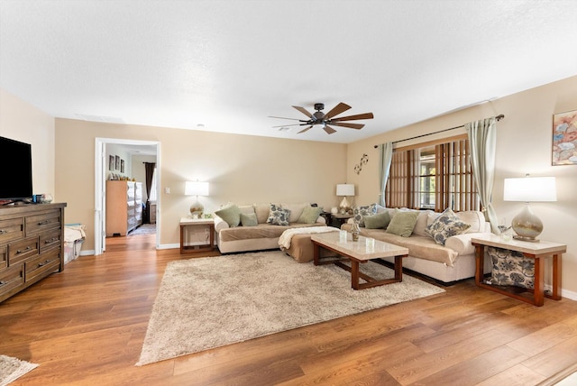 living room with a ceiling fan, visible vents, baseboards, and light wood-style floors