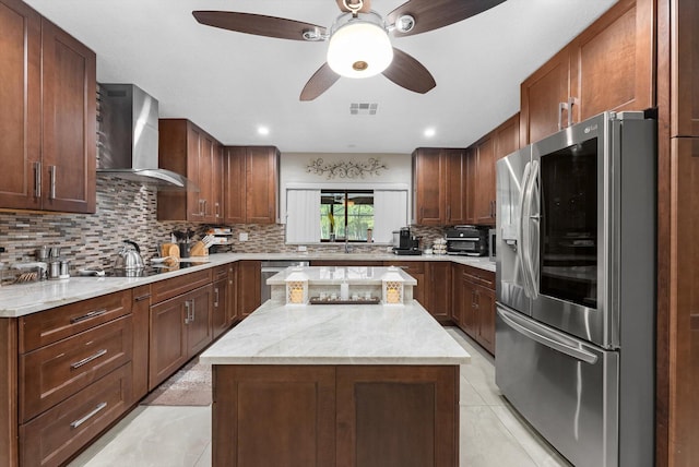 kitchen with wall chimney range hood, appliances with stainless steel finishes, visible vents, ceiling fan, and backsplash