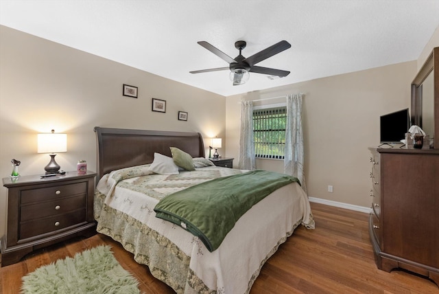 bedroom with baseboards, wood finished floors, and a ceiling fan