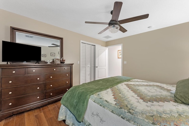 bedroom featuring dark wood-style flooring, visible vents, ceiling fan, and a closet