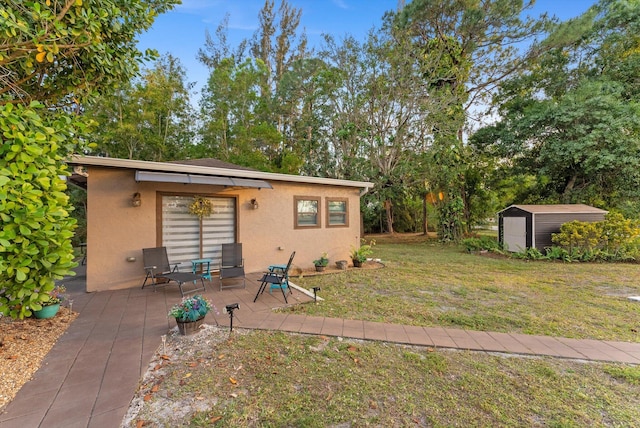 exterior space with an outdoor structure, a storage unit, a patio area, a lawn, and stucco siding