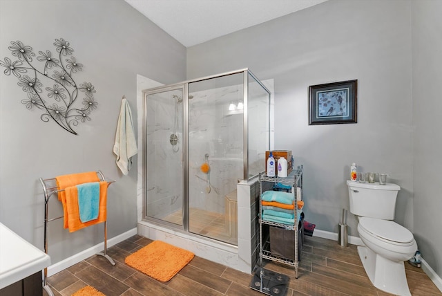 bathroom with baseboards, a stall shower, wood finish floors, and toilet