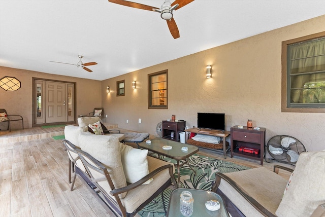 living room featuring wood finished floors, a ceiling fan, and a textured wall
