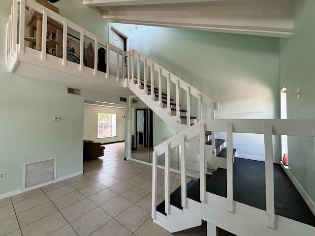 1894 NW Britt Rd, Stuart, FL 34994 - staircase with beam ceiling, a towering ceiling, tile patterned flooring, and baseboards