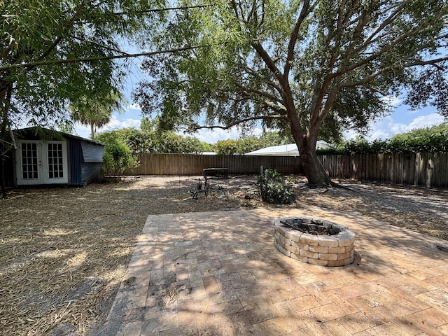 1894 NW Britt Rd, Stuart, FL 34994 - fenced backyard with french doors, a fire pit, and a patio area