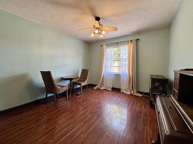1894 NW Britt Rd, Stuart, FL 34994 - sitting room featuring a wood stove, dark wood-style floors, ceiling fan, and baseboards