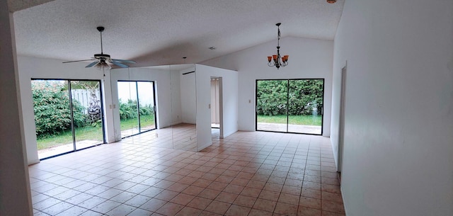 spare room with plenty of natural light, ceiling fan with notable chandelier, tile patterned floors, and vaulted ceiling