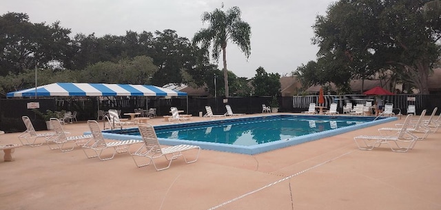 community pool with fence and a patio area