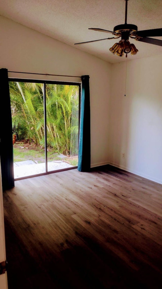 spare room with baseboards, ceiling fan, and wood finished floors