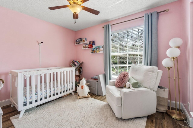 bedroom featuring baseboards, wood finished floors, and a nursery area
