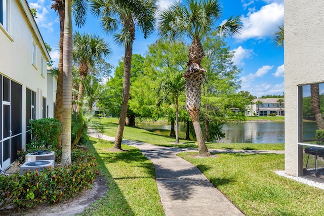 surrounding community with a water view and a lawn