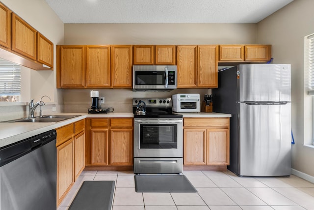 kitchen featuring a sink, light countertops, appliances with stainless steel finishes, and light tile patterned floors