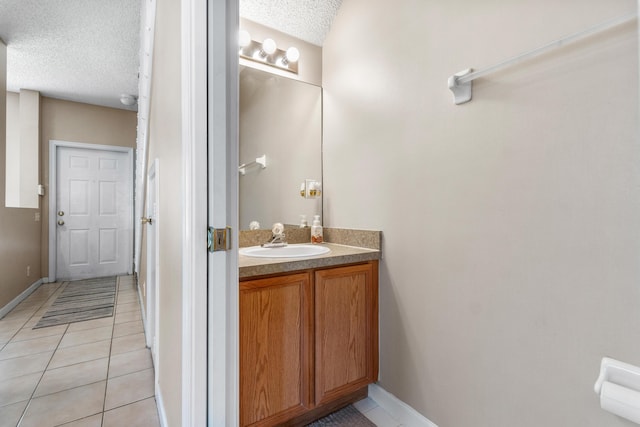 bathroom with baseboards, tile patterned flooring, vanity, and a textured ceiling