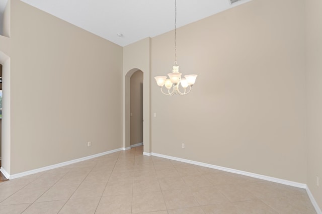 unfurnished room featuring light tile patterned flooring, baseboards, a notable chandelier, and arched walkways