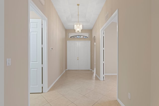 entryway with baseboards, visible vents, a chandelier, and light tile patterned floors