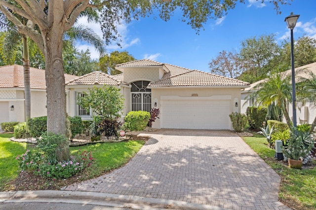 mediterranean / spanish-style house featuring a tile roof, driveway, stucco siding, and an attached garage