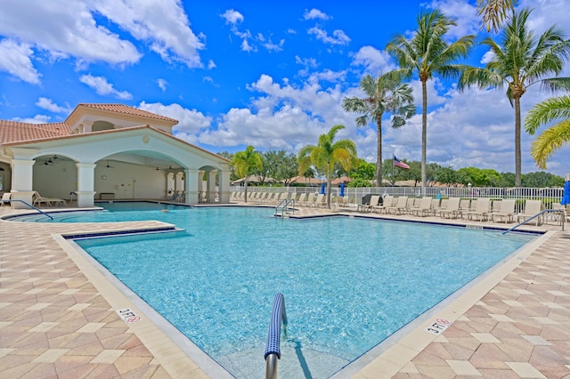 pool with a patio, fence, and a ceiling fan